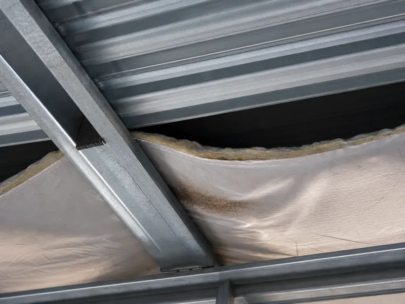 Aislamiento descolgado entre las correas de un edificio metálico, con la cámara de aire que se forma contra la chapa fría
