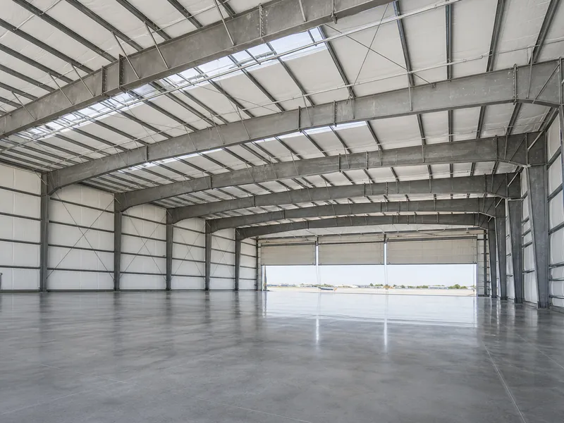 Interior de hangar metálico de claro libre sin columnas intermedias, con marcos rígidos de acero a la vista